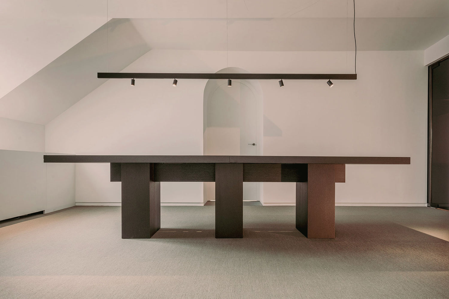 Minimal white conference room with a massive black wooden conference table, creating an elegant and modern interior.