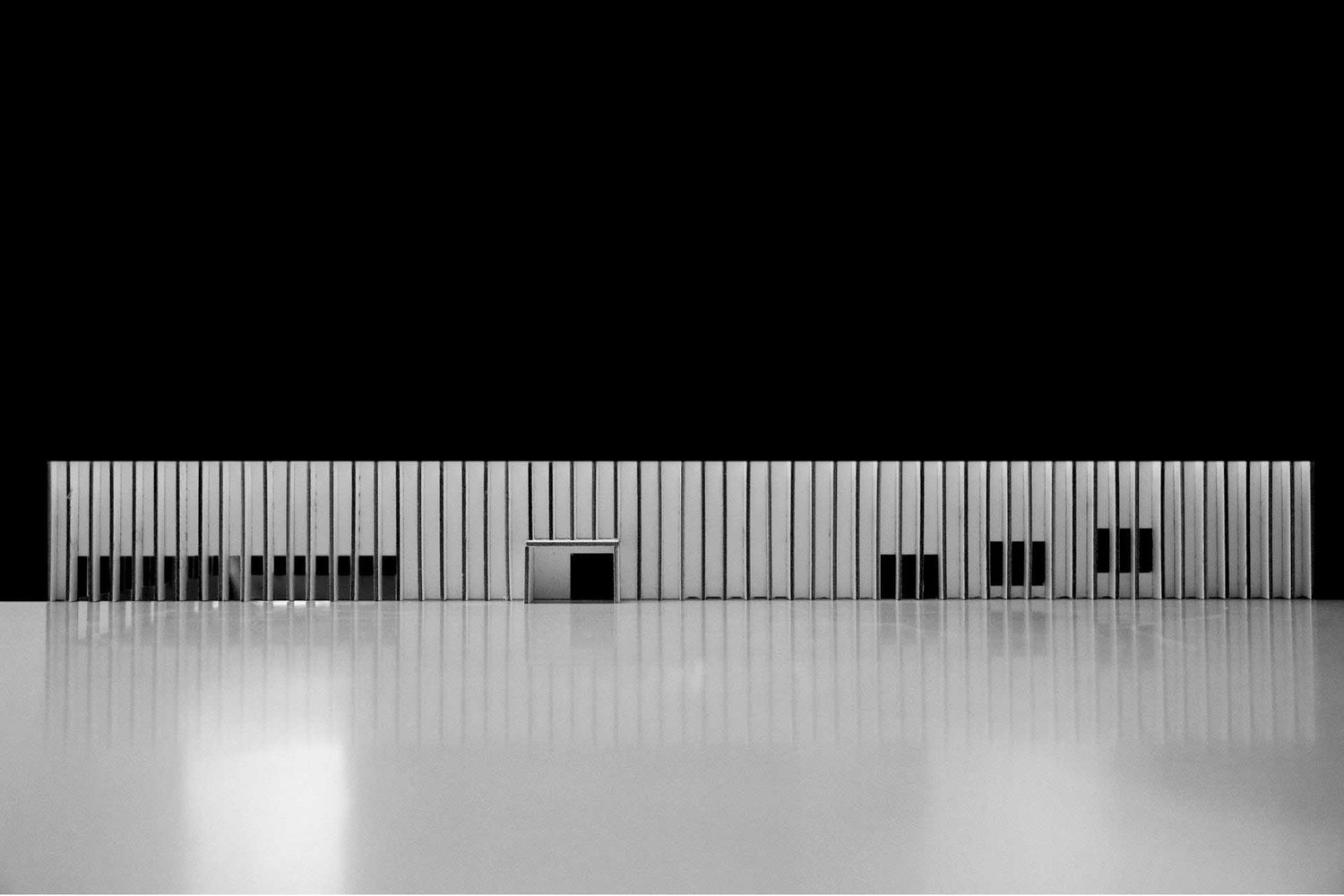 White architectural maquette, facade of a school, with a black background.